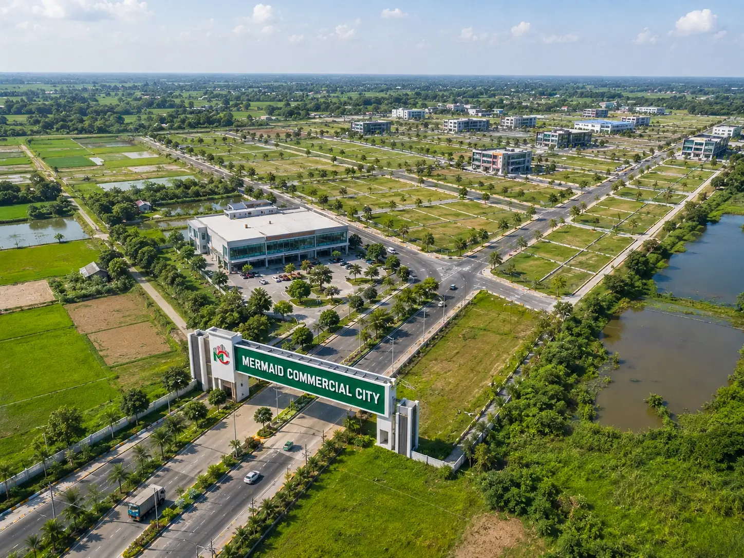 Mermaid Commercial City entrance gate with green plots, road network, water body, and commercial buildings